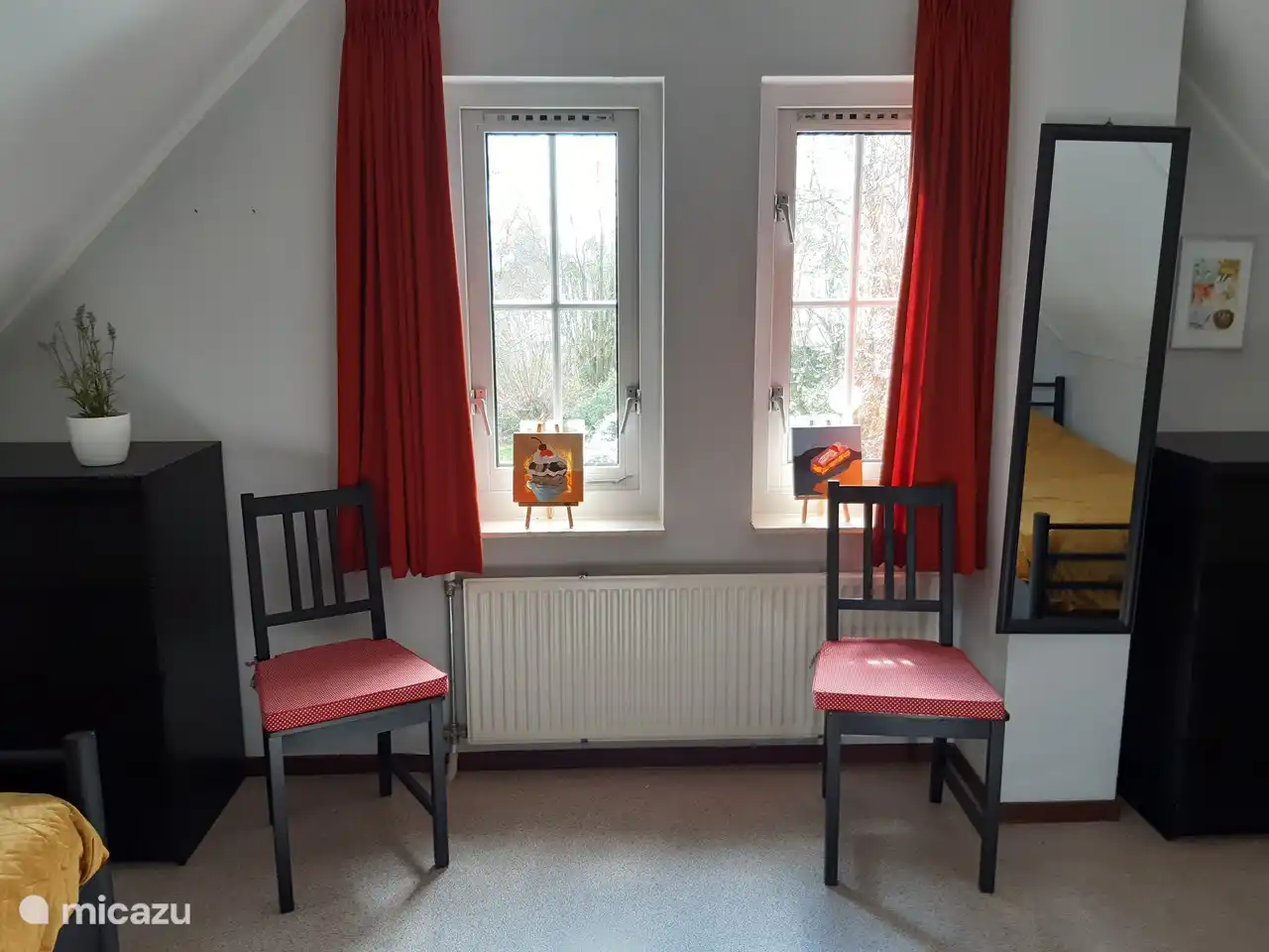 Bedroom with two single beds. With handy chairs to hang clothes over, for example. Chests of drawers also present.