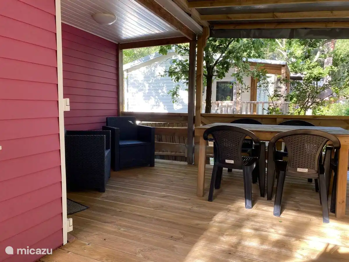 Belle terrasse couverte spacieuse avec table à manger et salon