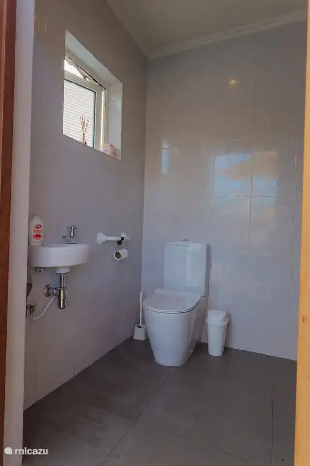 Der Toilettenraum neben dem Pool mit Toilette und Dusche