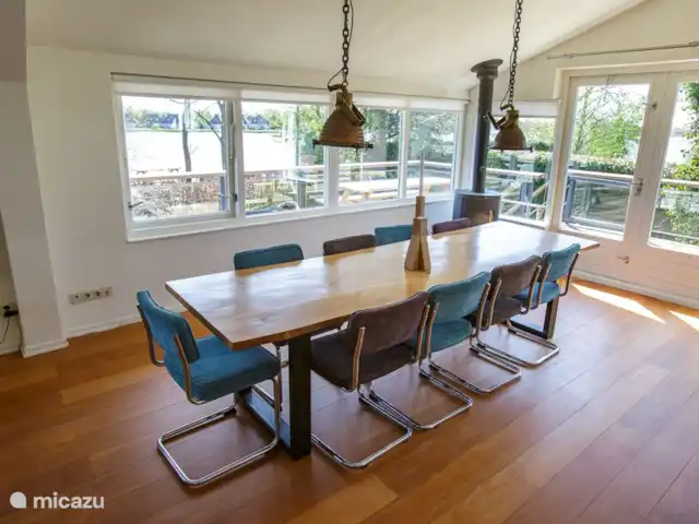Villa de vacances spacieuse sur le lac frison | Pays-Bas, Frise, Eernewoude - villa Grande table à manger confortable avec vue sur l'eau, à côté du poêle à bois.