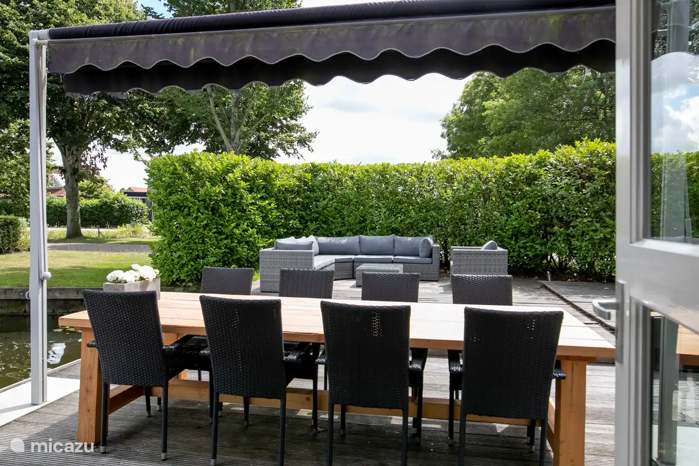 Terrasse avec grande table avec 8 chaises et un ensemble salon.