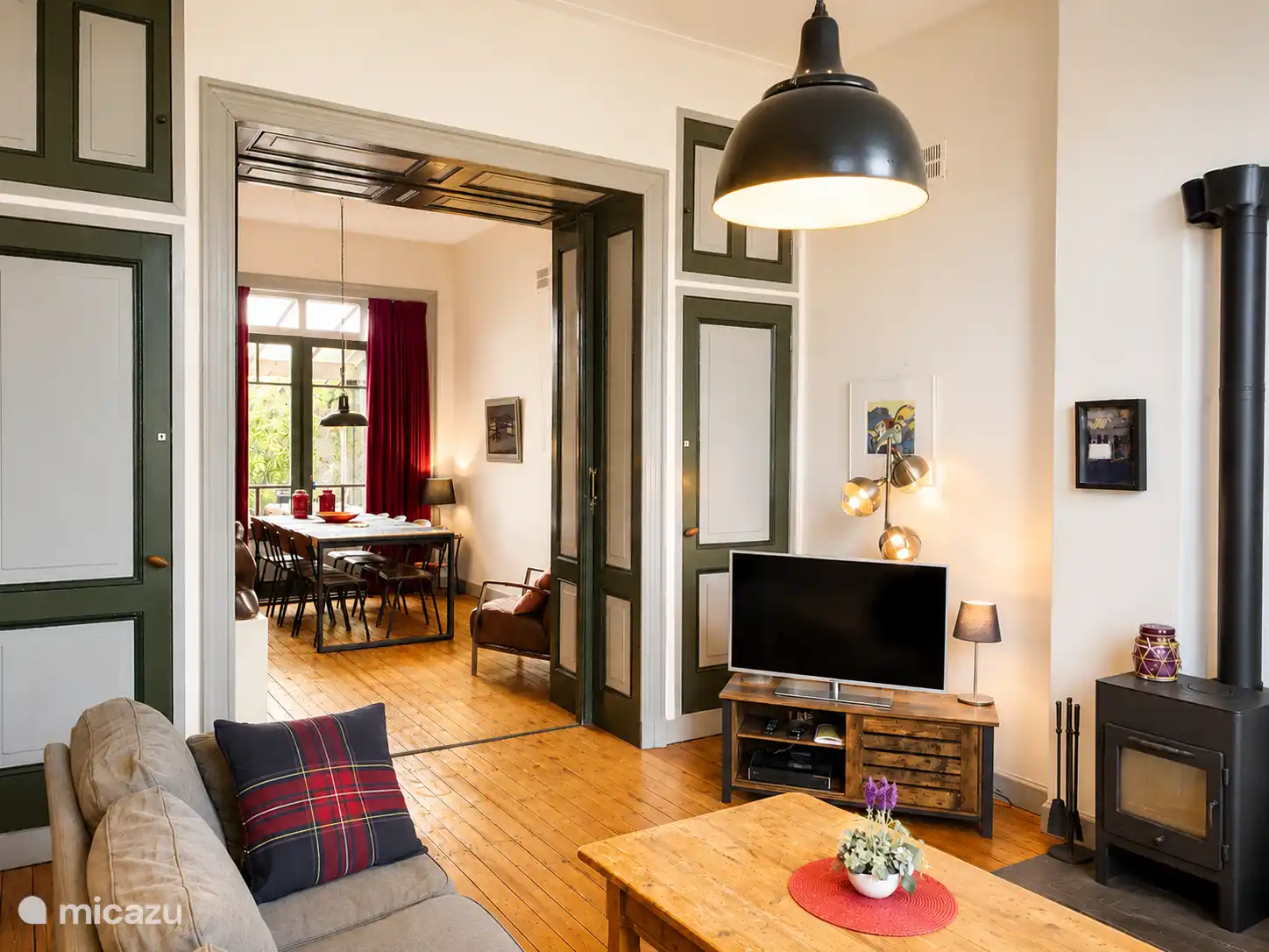 Lichte en uitnodigende woonkamer met originele houten vloeren, hoge plafonds en elegante details uit de bouwperiode. Ontspan op de comfortabele banken - perfect om samen tijd door te brengen. 