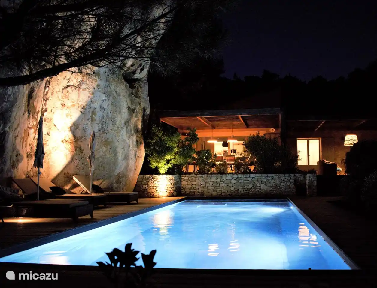 Abendstimmung mit beleuchtetem Felsen und Pool