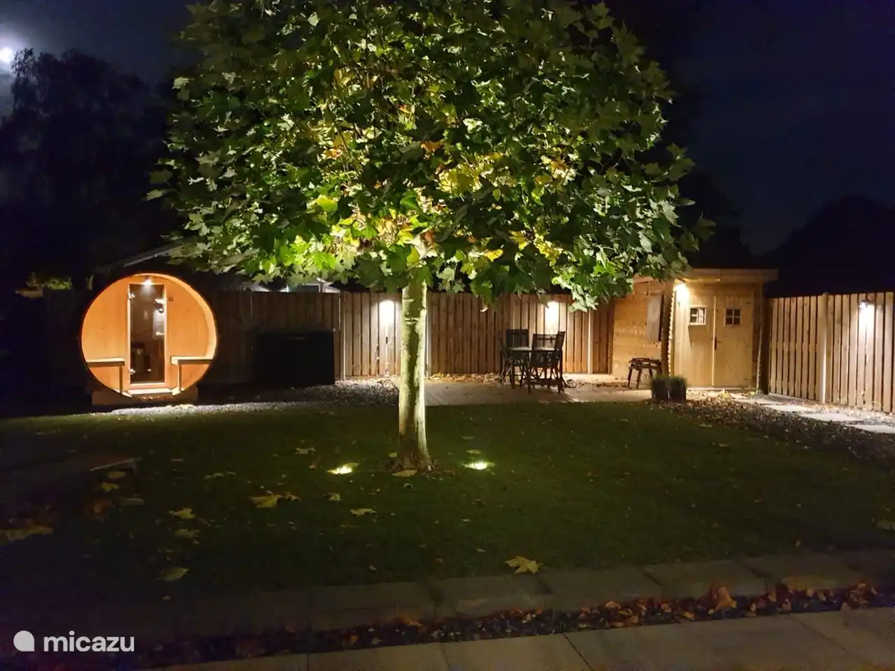 Der Garten mit der beleuchteten Sauna und der schönen Gartenbeleuchtung am Abend.