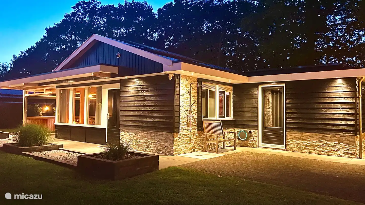 El bungalow está bellamente iluminado por la noche.