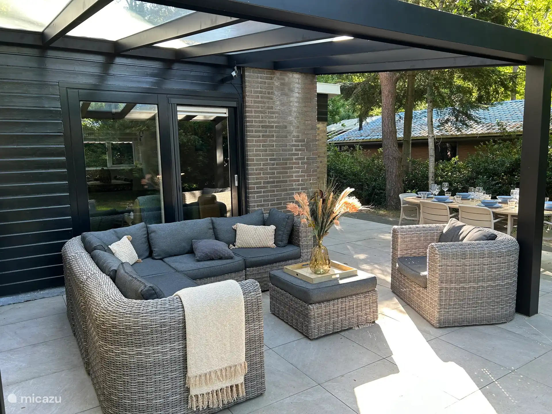 Die Terrasse mit Lounge unter dem Vordach