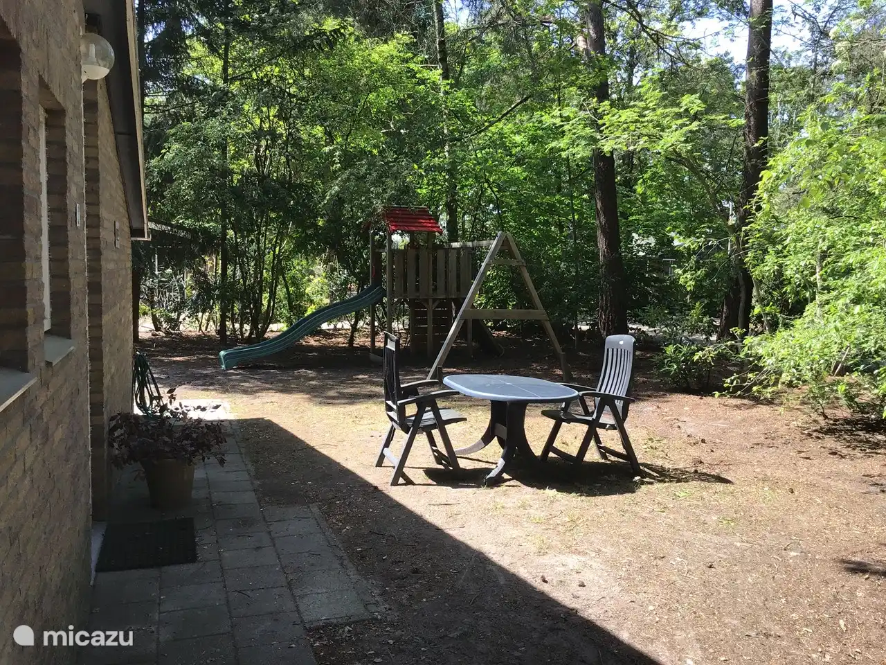 Seite des Hauses mit den Spielgeräten im Hintergrund.