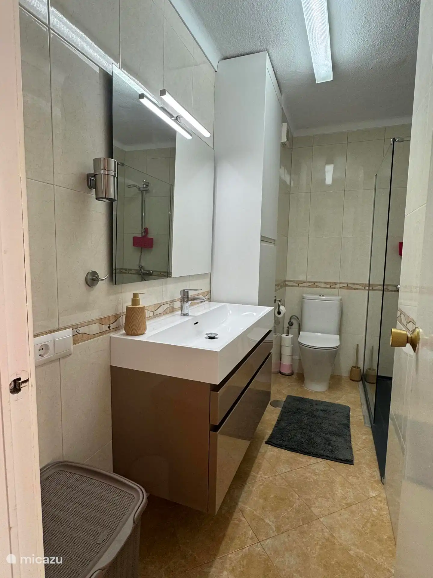 Voll ausgestattetes Badezimmer mit ebenerdiger Dusche und erhöhtem WC.