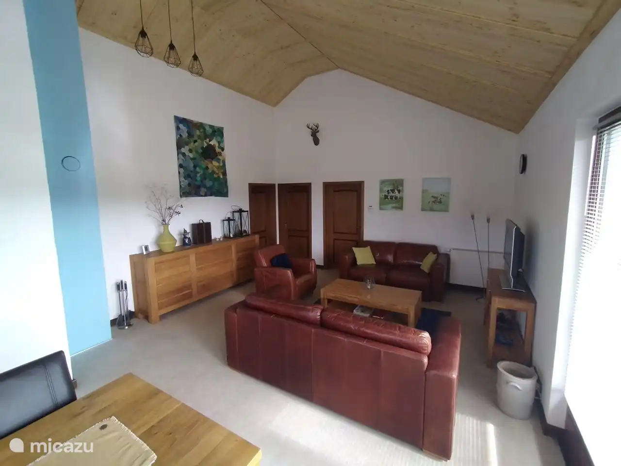 Wohnzimmer mit angrenzender Küche und Tür zur Terrasse.