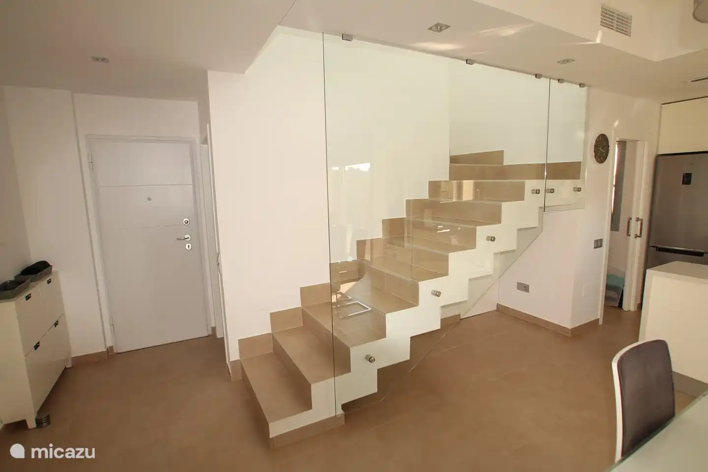 Opgang naar de eerste verdieping met open zicht naar de woonkamer door de glazen wand.