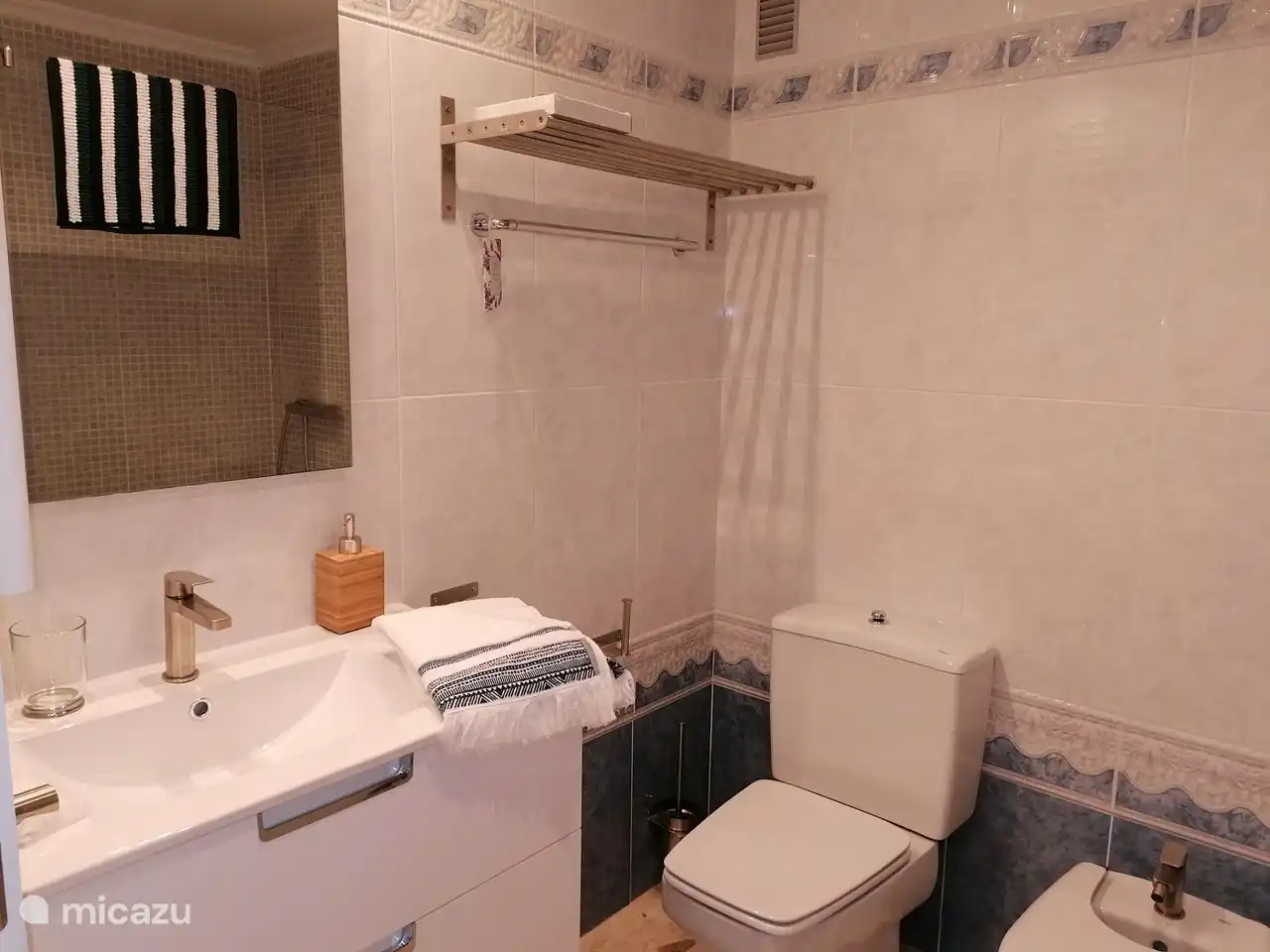 Das Hauptschlafzimmer verfügt über ein eigenes Bad. Hier gibt es eine geräumige ebenerdige Dusche, Heizung, Toilette und Bidet sowie eine Waschbecken-Kombination mit geräumigen Möbeln. Handtücher werden gestellt.