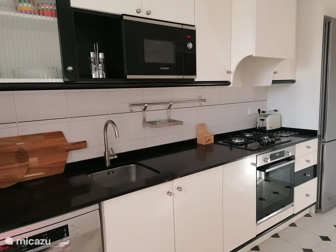 Die Küche hat eine Natursteinplatte und ein komplettes Inventar.