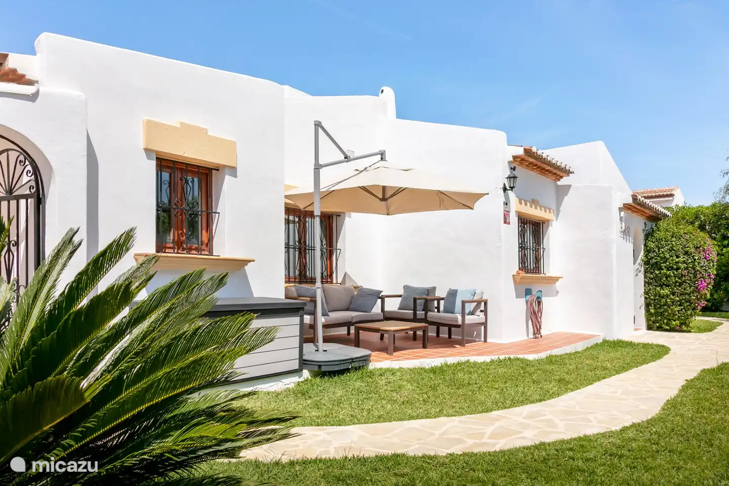 Ein ruhiger Sitzbereich hinter dem Haus, wo Sie etwas Schatten unter dem Sonnenschirm genießen können.