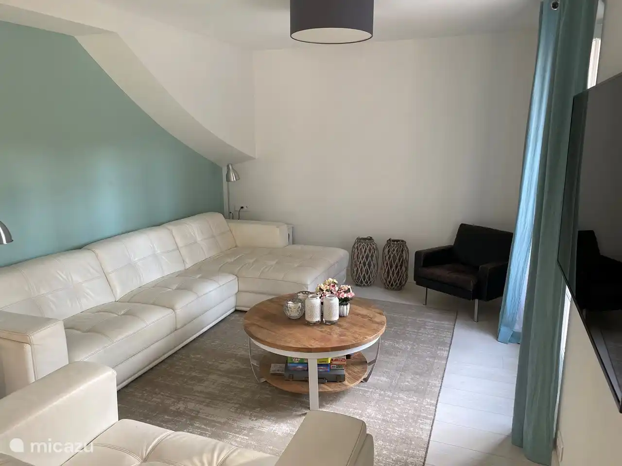 Salon avec porte-patio donnant sur la cour arrière. Grand canapé 4 places en cuir blanc et causeuse