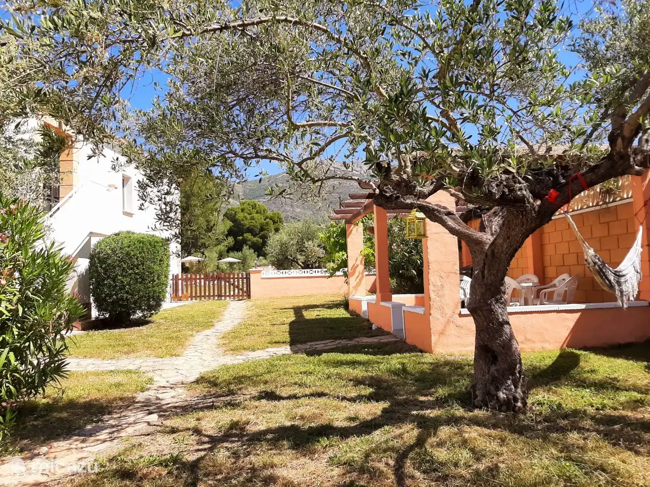 A la izquierda la entrada al apartamento. A la derecha la terraza privada con barbacoa de carbón y hamaca. Siga recto por la puerta de entrada a la piscina.
