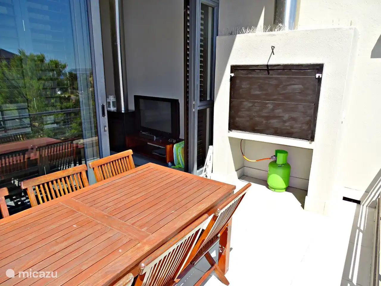 Esstisch auf sonnigem Balkon mit Gasgrill