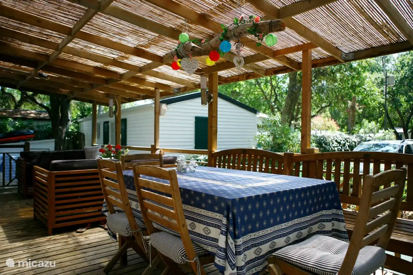 Amplia terraza, parcialmente cubierta con un juego de salón, una gran mesa de comedor y tumbonas
