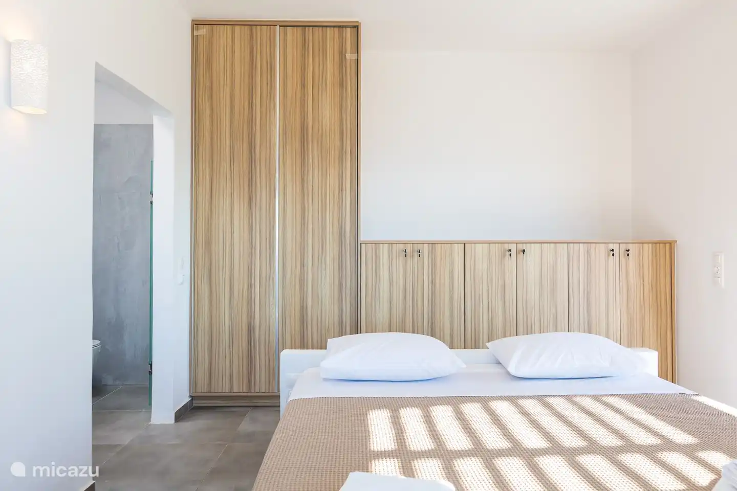 Das große Bett ist zentral für den Raum und Sie können den ganzen Weg herumlaufen mit viel Stauraum für die Kleidung.