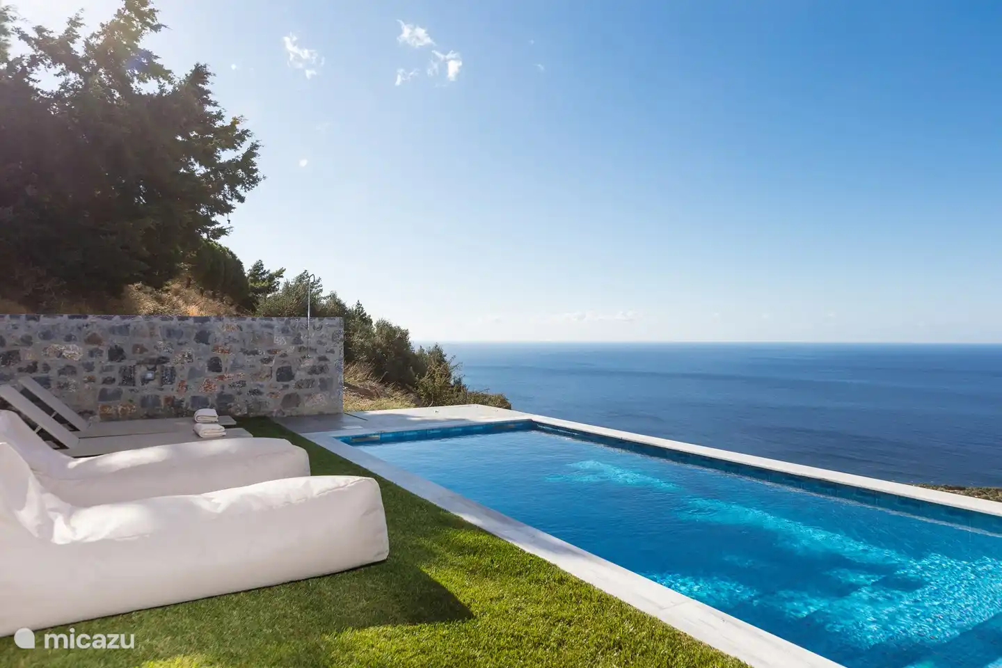 Auf dem Rasen gibt es Sonnenliegen, einen Sonnenschirm und Lounge-Kissen.