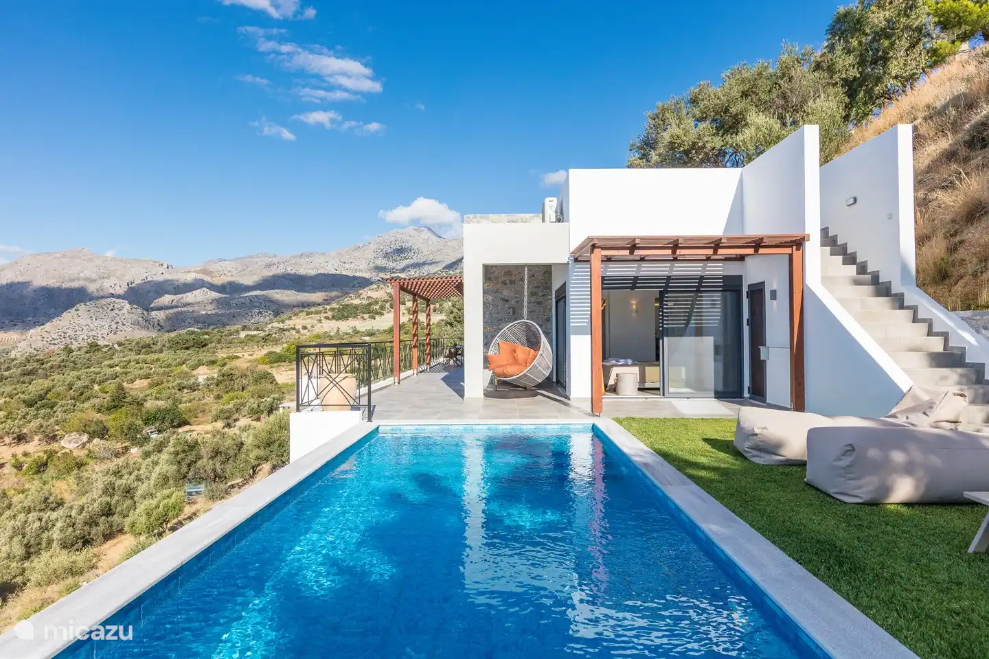 Neben dem Pool auf der Terrasse befindet sich ein 2-Personen Hängestuhl mit Kissen.