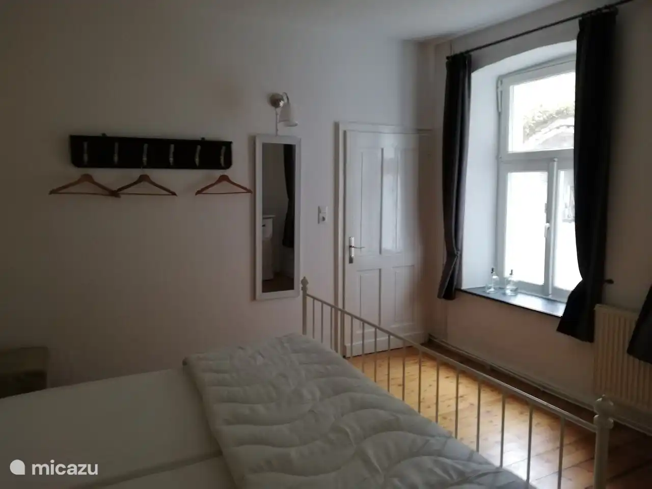 Schlafzimmer mit Doppelbett, Kommode und Kinderbett.