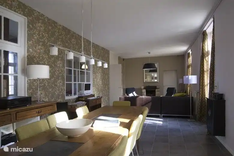 Le grand salon avec cheminée dispose d'un joli coin salon avec canapé lounge et d'un coin repas pouvant accueillir 8 personnes.