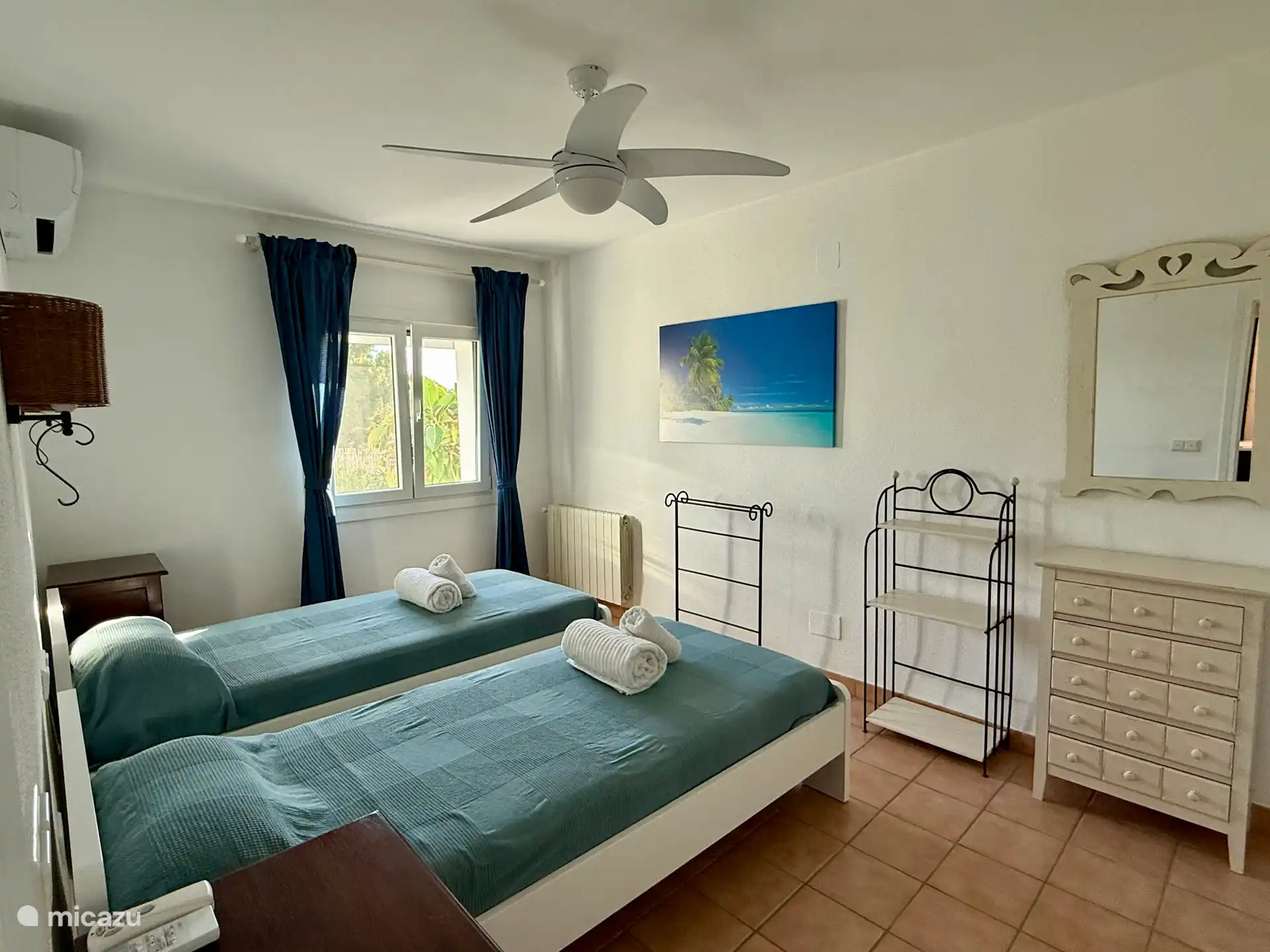 Chambre 2 avec : lits simples, climatisation, ventilateur de plafond et placard de rangement.