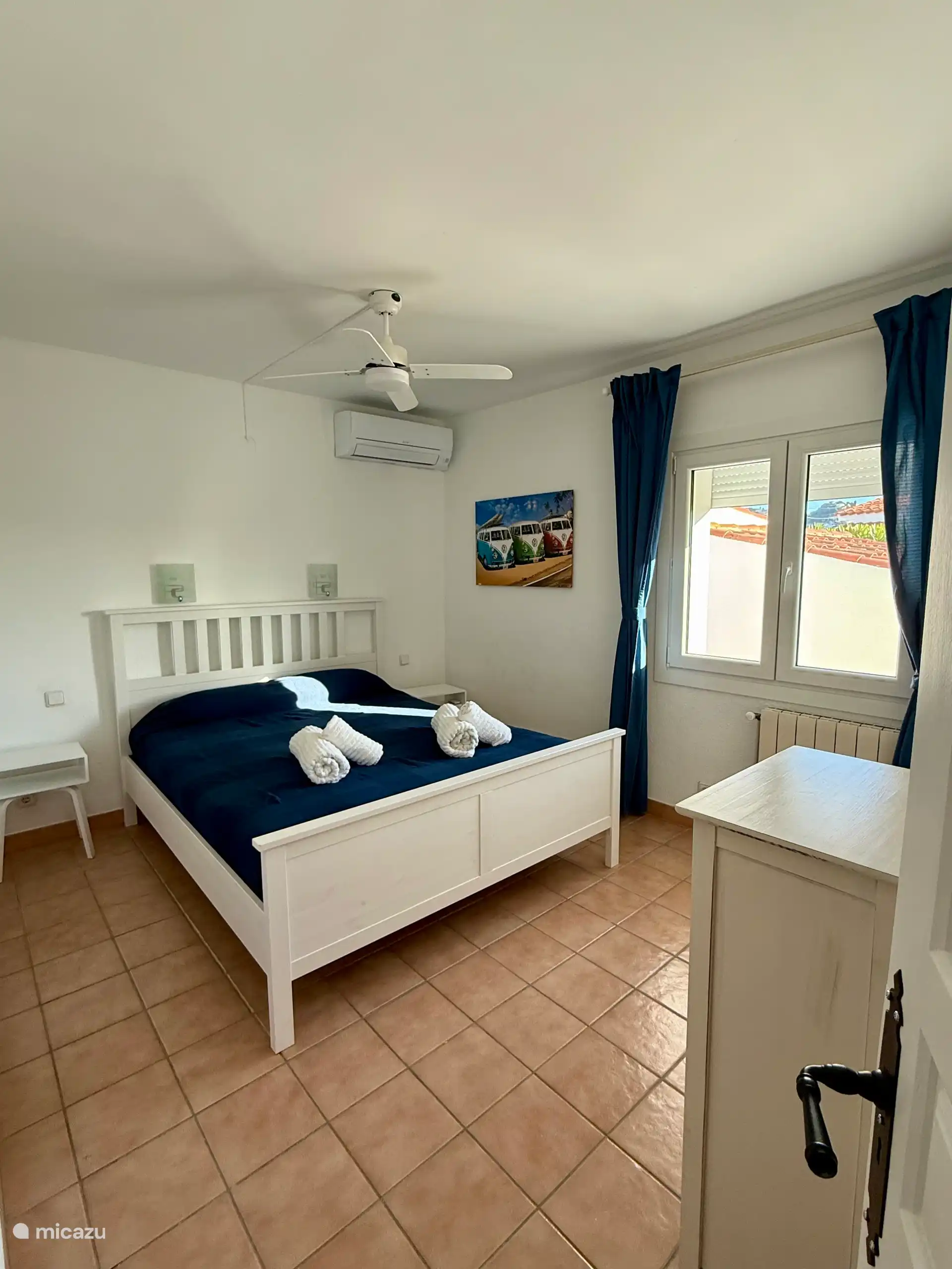 Chambre 1 avec : lit double, climatisation, ventilateur de plafond et placard de rangement.