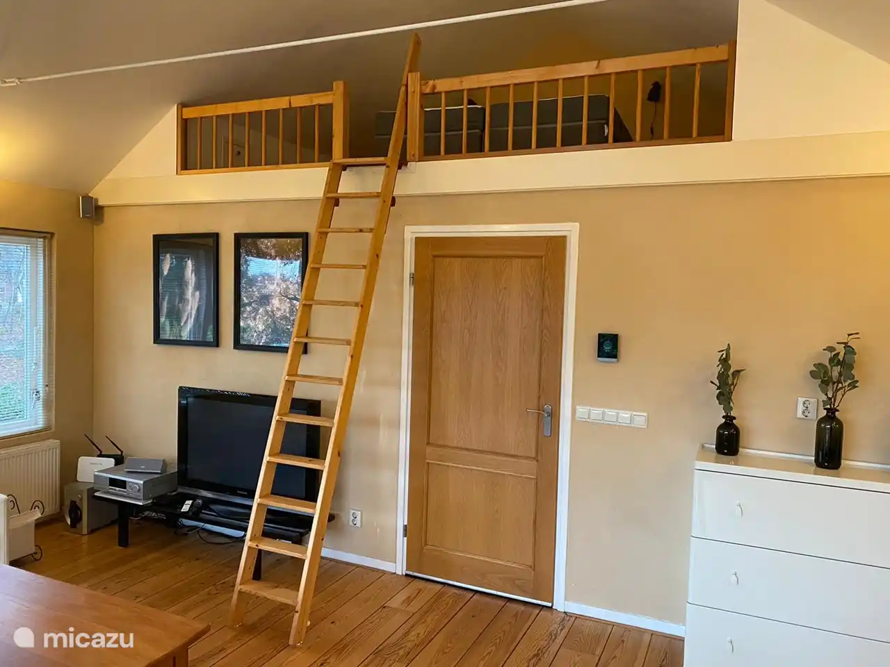 Eine Treppe im Wohnzimmer führt auf den Dachboden mit einem Doppelbett.