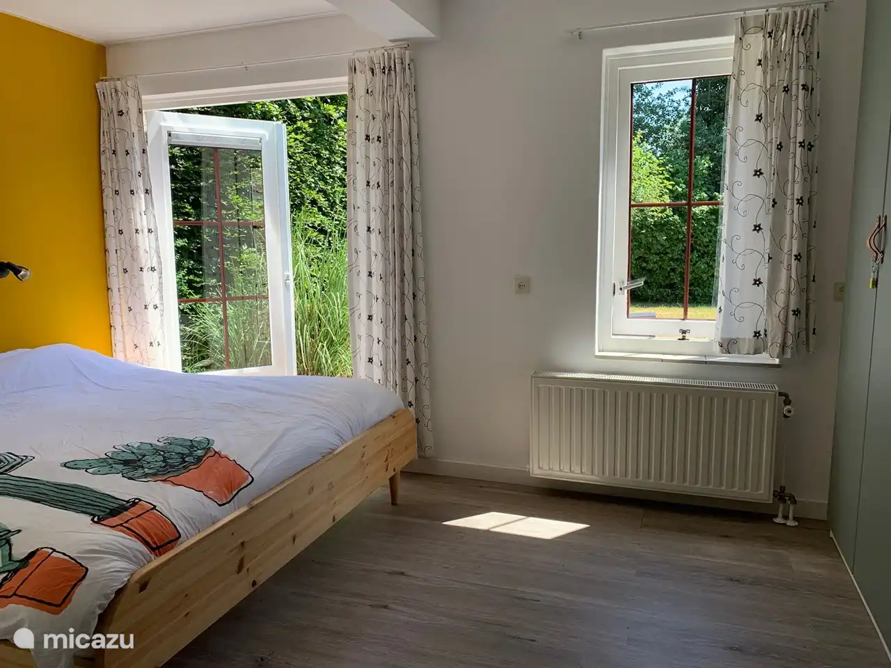 Schlafzimmer im Erdgeschoss mit Doppelbett, Terrassentüren zum Hinterhof, Waschbecken und Schrankraum.