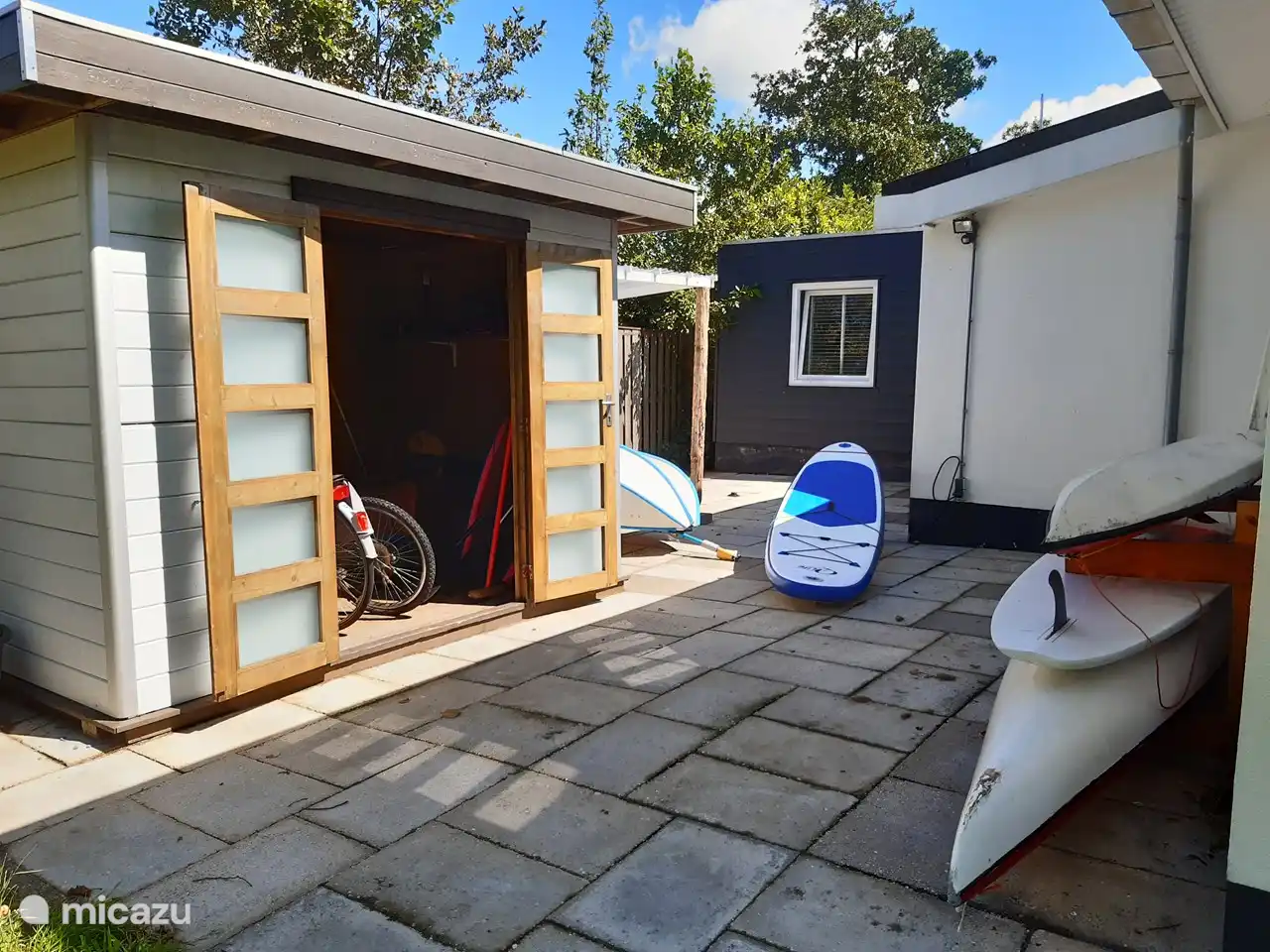 Gartenhaus mit Stützbrett, Kajaks, Ruderboot und Surfbrettern