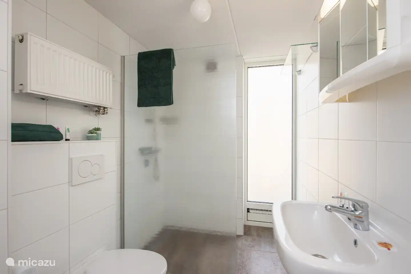 Badezimmer mit Toilette, Waschbecken und ebenerdiger Dusche