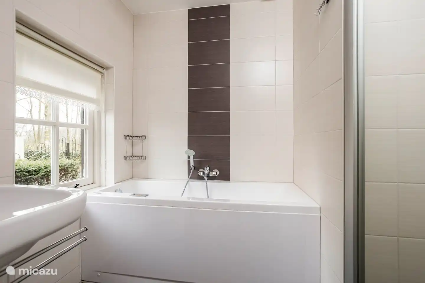 Salle de bain avec bain à remous, douche à l'italienne et lavabo.