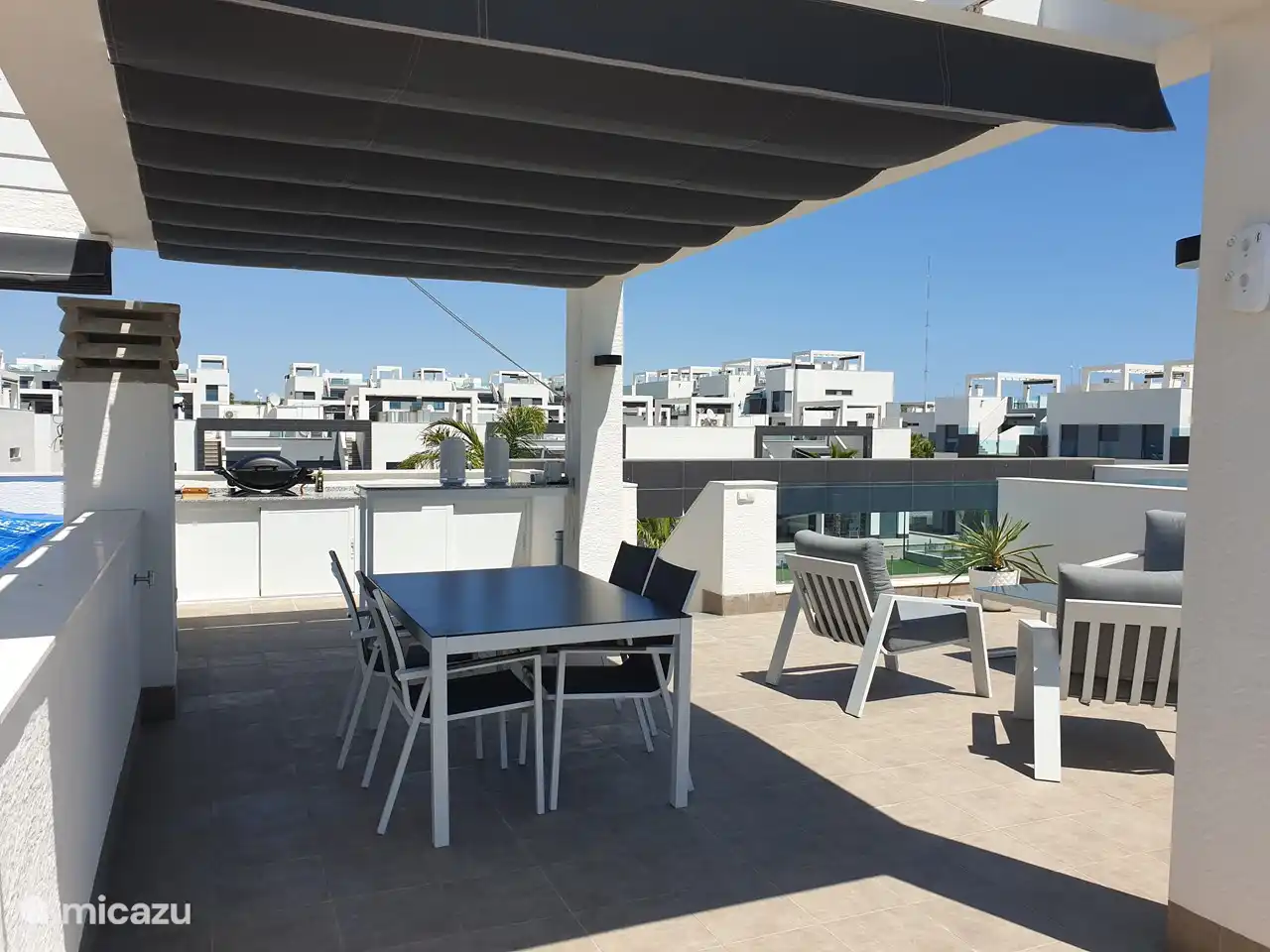 La azotea de 70 m2 está equipada con una cocina exterior con barbacoa de gas y fregadero, una barra alta con 2 taburetes, un comedor para 4 personas con protección solar horizontal, 2 tumbonas con lujosos cojines y una sombrilla, una zona de estar cómoda zona con sofá de 2 plazas y 2 sillones independientes. También ducha al aire libre