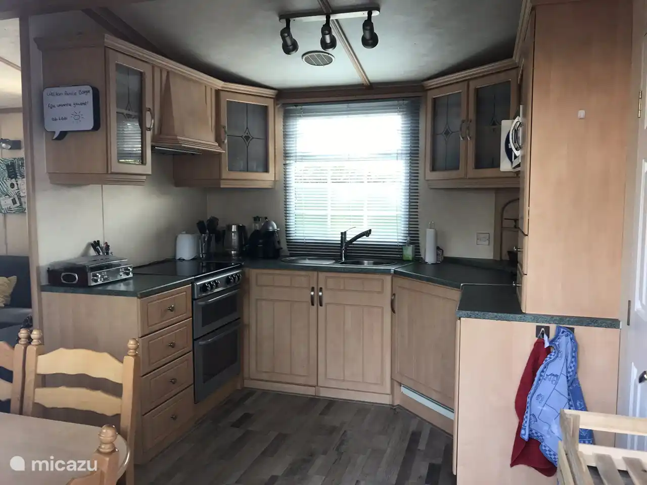 Grote uitgebreide open keuken met dubbele oven, koelkast, vriezer, magnetron, waterkoker, koffieapparaat en toaster.