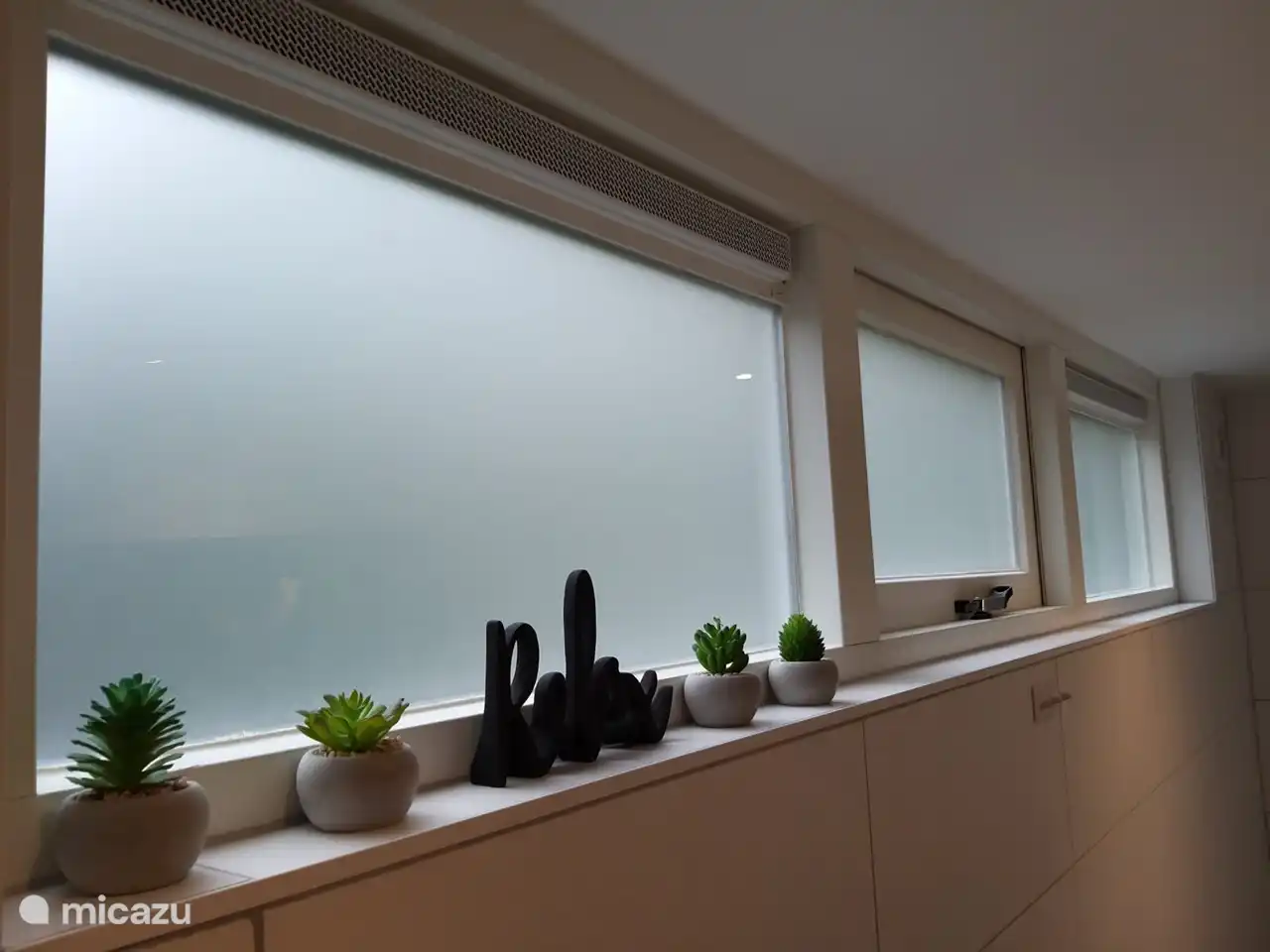 Durch die vielen Fenster fällt viel natürliches Tageslicht in das Badezimmer. Die Privatsphäre wird durch das Milchglas gewährleistet.