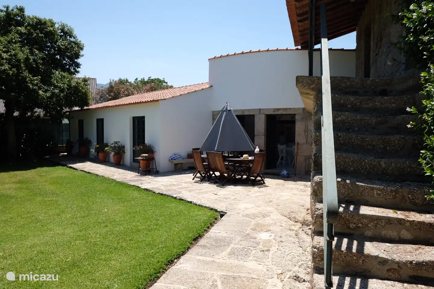 Blick auf die Terrasse und rechts die alte Treppe zur schattigen Veranda.