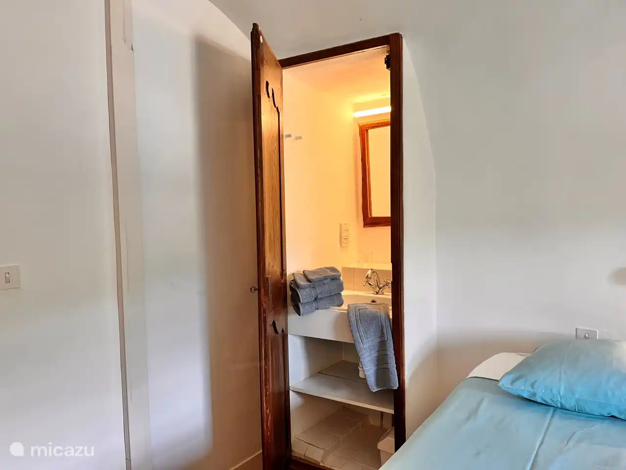 De wastafel achter de fraai bewerkte notenhouten deur in de slaapkamer.
