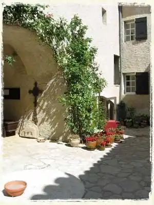 Der Innenhof, Oase mit seinem Rosenbogen und vielen Topfpflanzen.