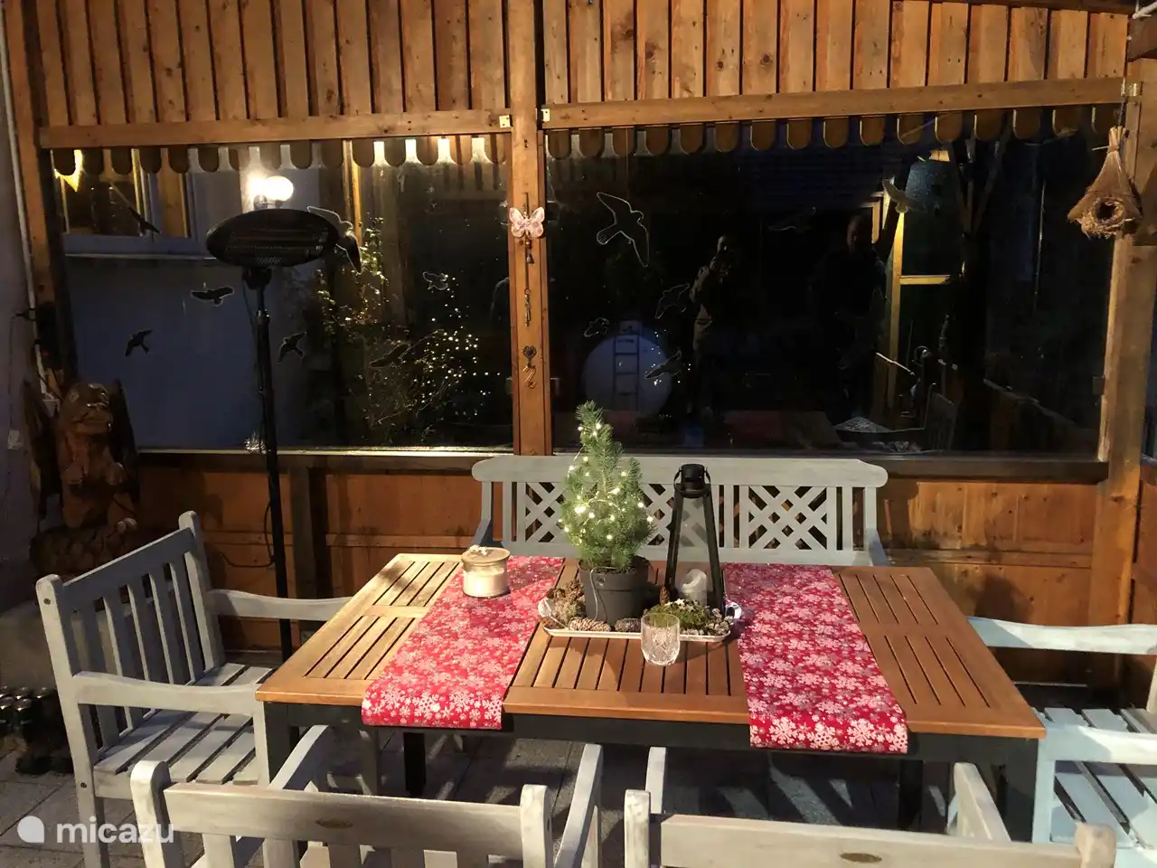 Véranda avec salon de jardin et éclairage cosy et décorée pour Noël.