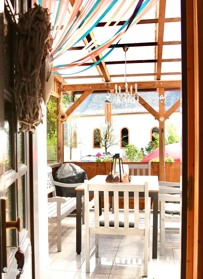 Vue depuis la porte sur le porche et le jardin avec l'église en arrière-plan.