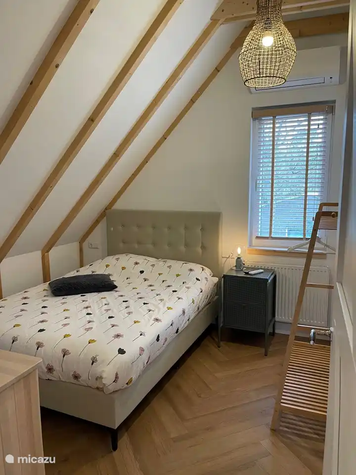Schlafzimmer (3) mit Boxspring, TV und offenem Kleiderständer.