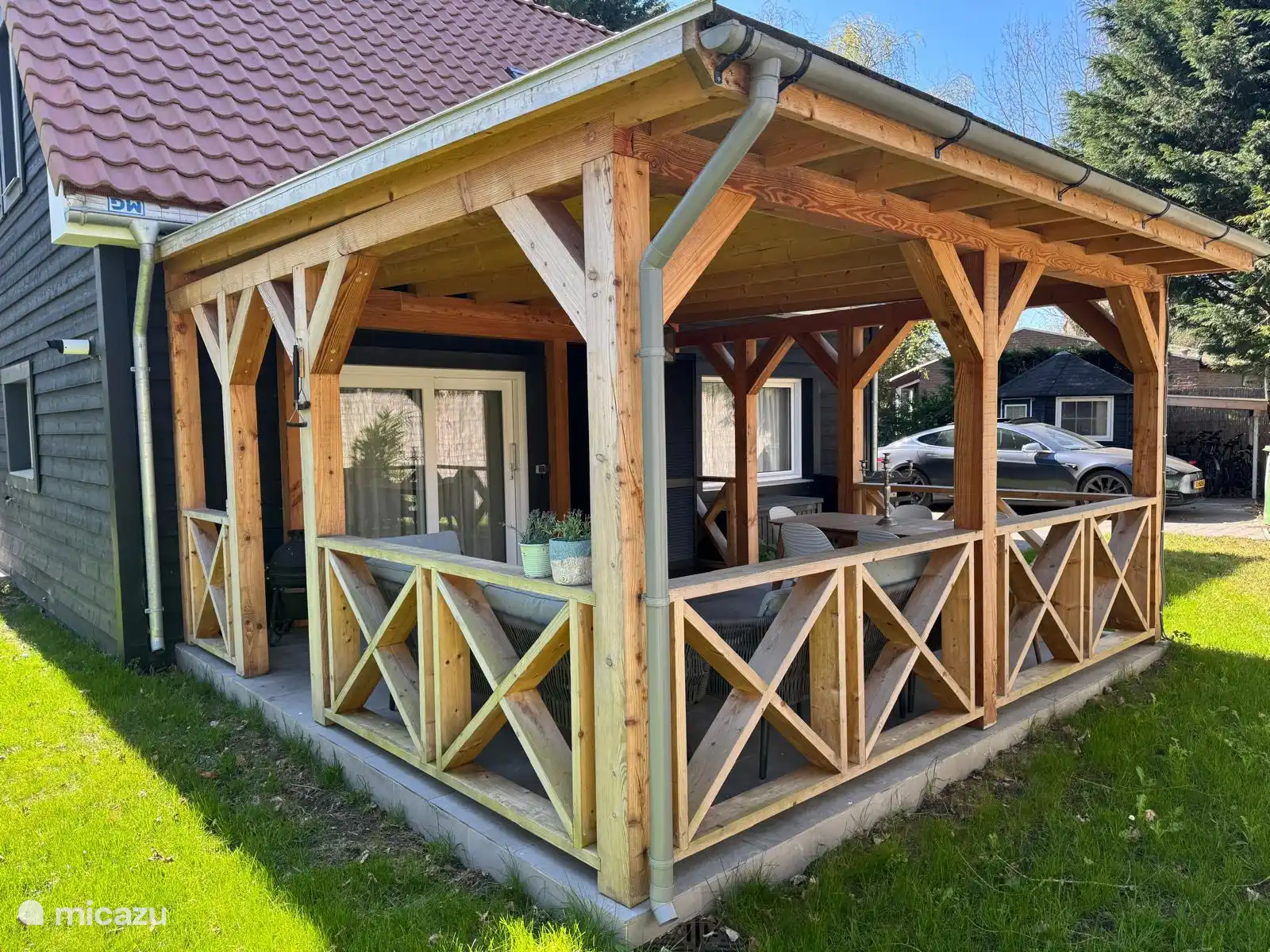 Gemütliche Holzveranda mit Sitzgelegenheiten und viel Licht. Ideal, um in Ruhe draußen zu sitzen, geschützt vor Sonne oder Regen. Eine attraktive Erweiterung des Hauses!