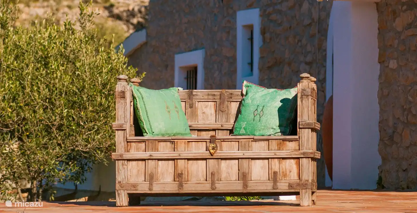 Dies ist die Seitenwand des Hauses mit einer Terrasse und einer antiken Holzbank