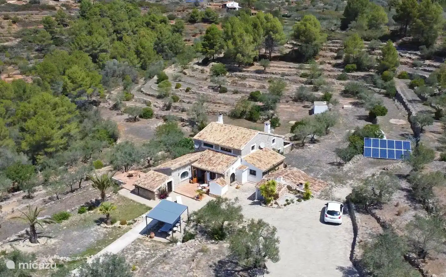 Dies ist ein Übersichtsfoto, auf dem das Haus, die Gebäude, die Sonnenkollektoren und der Parkplatz deutlich zu sehen sind.