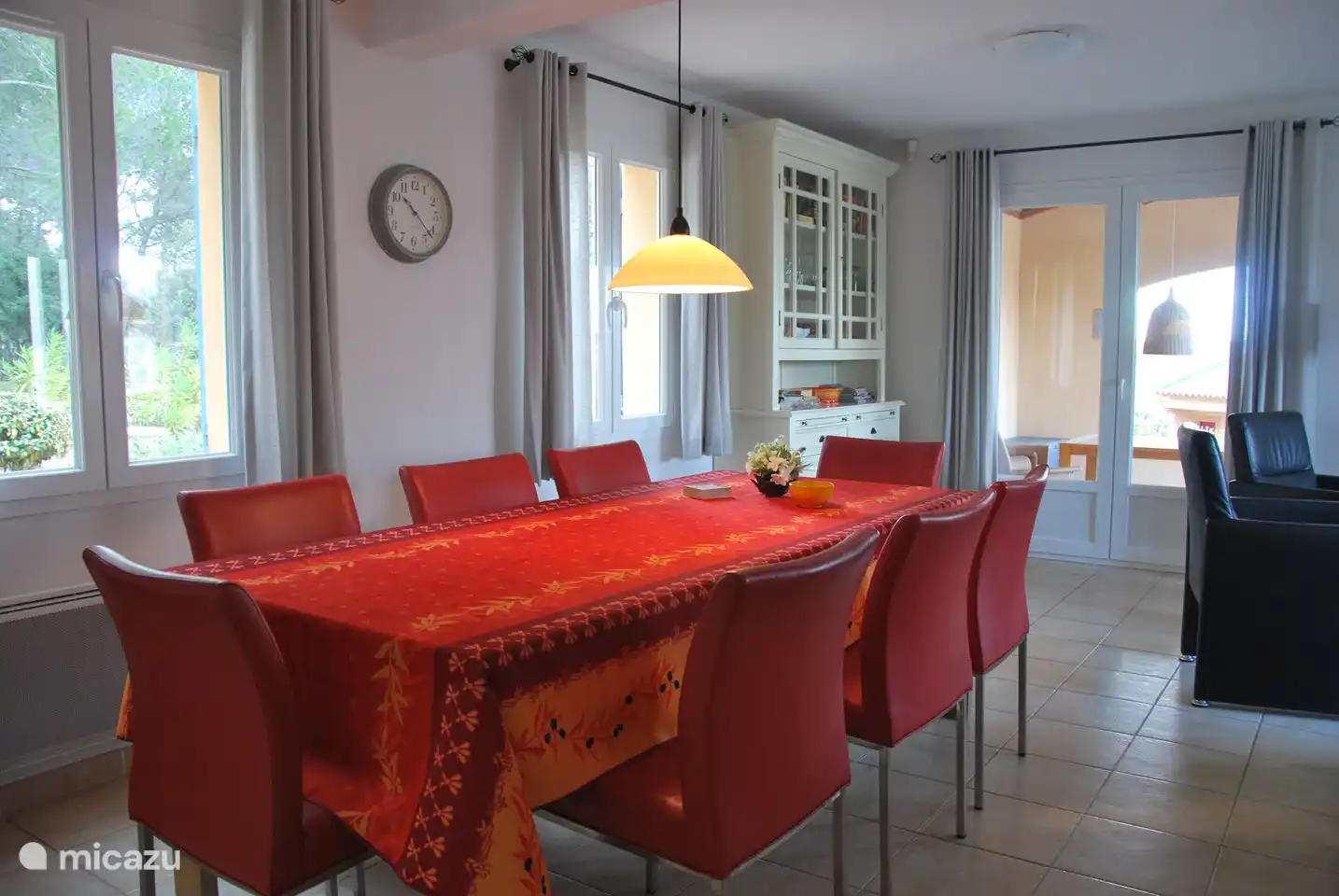 Geräumiger Essbereich mit großem Tisch, 8 Luxusstühlen. Zugang zur überdachten Terrasse und zum Garten dahinter.