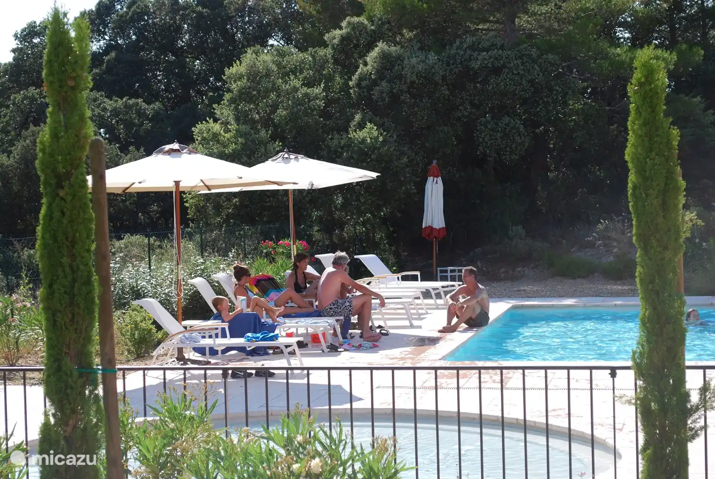 Große Auswahl an Sonnenliegen und Sonnenschirmen auf der geräumigen Terrasse rund um den Pool mit separatem Kinderbecken