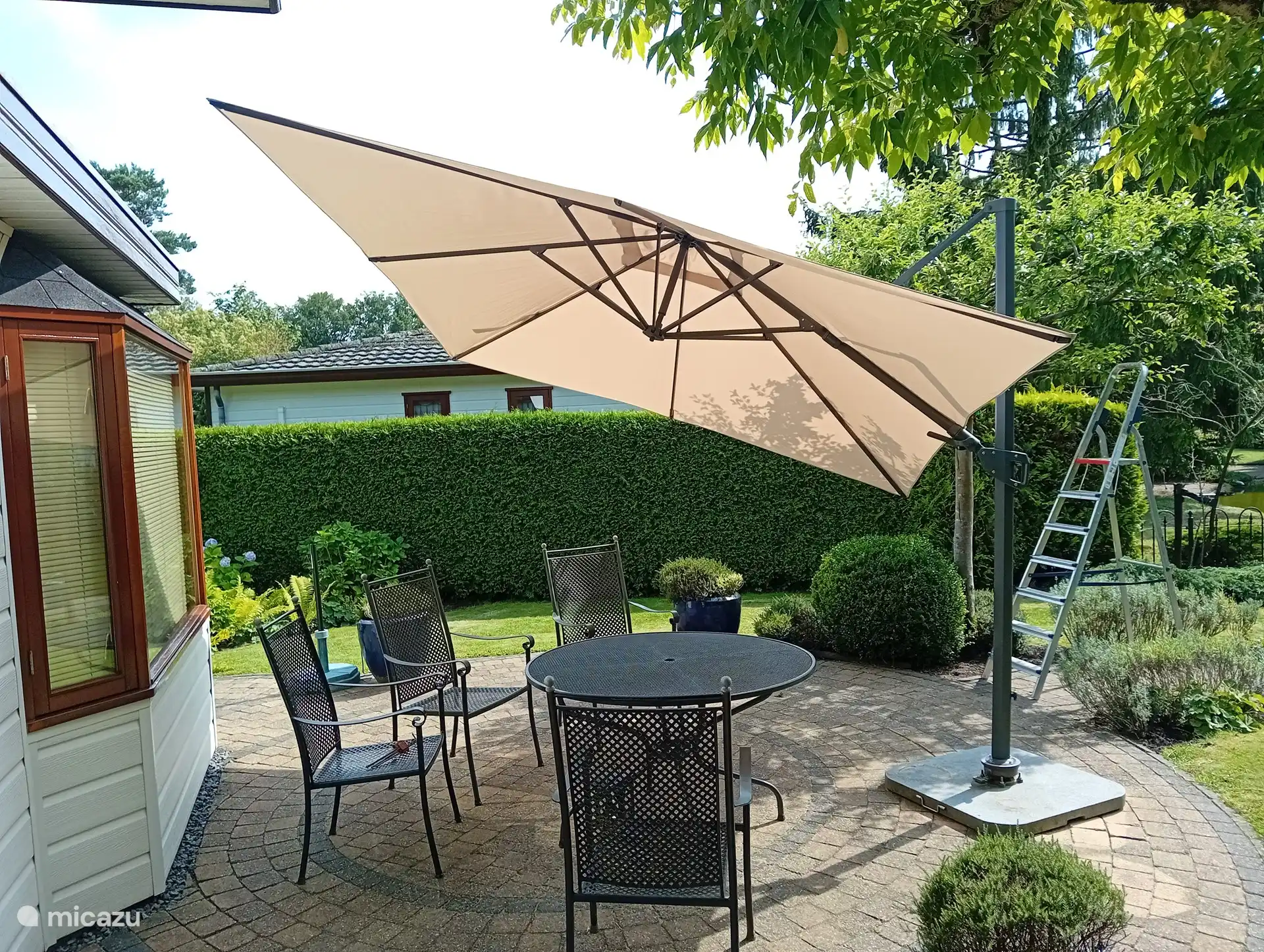 The main seat on the sunny side with possibly shade from the floating parasol or the ornamental apple tree.