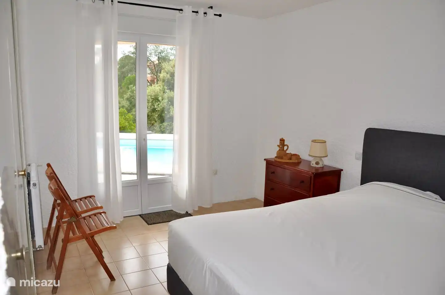 Geräumiges Schlafzimmer (5) im Erdgeschoss, ausgestattet mit einem komfortablen Boxspringbett, mit Terrassentüren zur Terrasse und direktem Zugang zum Swimmingpool.