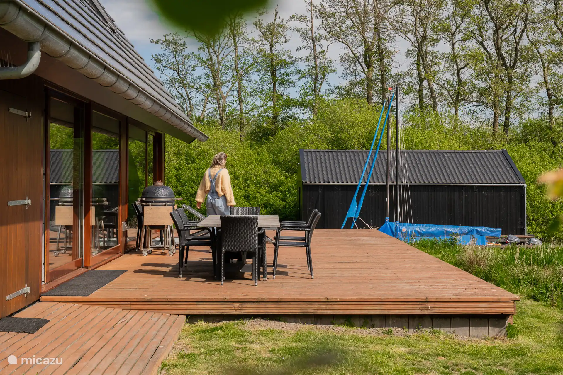 Encantadora terraza espaciosa con mesa de jardín y una gran barbacoa Kamado Takumi.